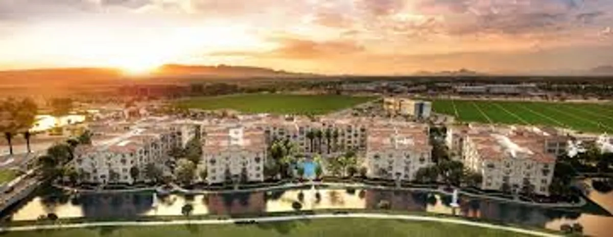 A tranquil exterior shot taken at sunset, revealing landscaped gardens, elegant water features, a view of residential buildings, and spaces for outdoor gatherings. The setting feels peaceful yet social, suggesting post-work relaxation and community engagement.