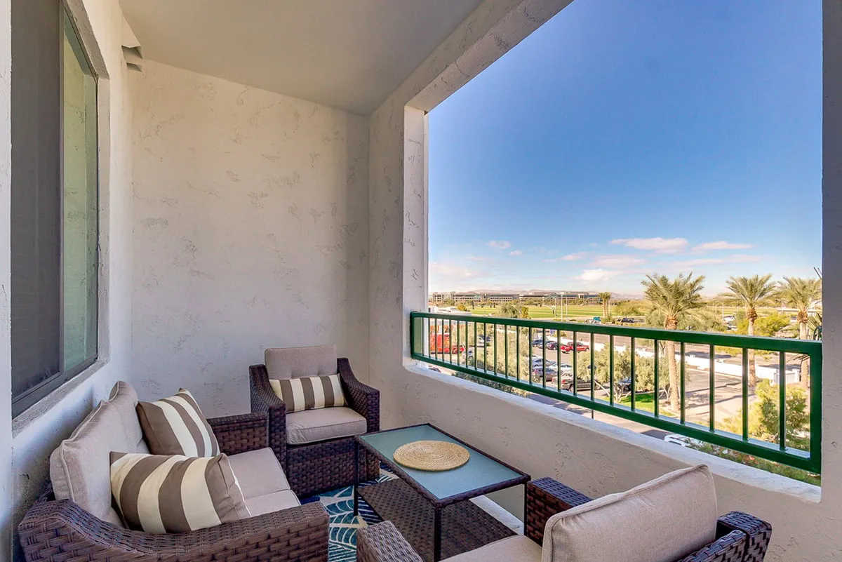A serene balcony scene with stylish seating and a decorative table, overlooking lush greenery. The area offers both intimate and social settings, perfect for enjoying morning coffee, sunset cocktails, or hosting small gatherings while taking in the scenic views.